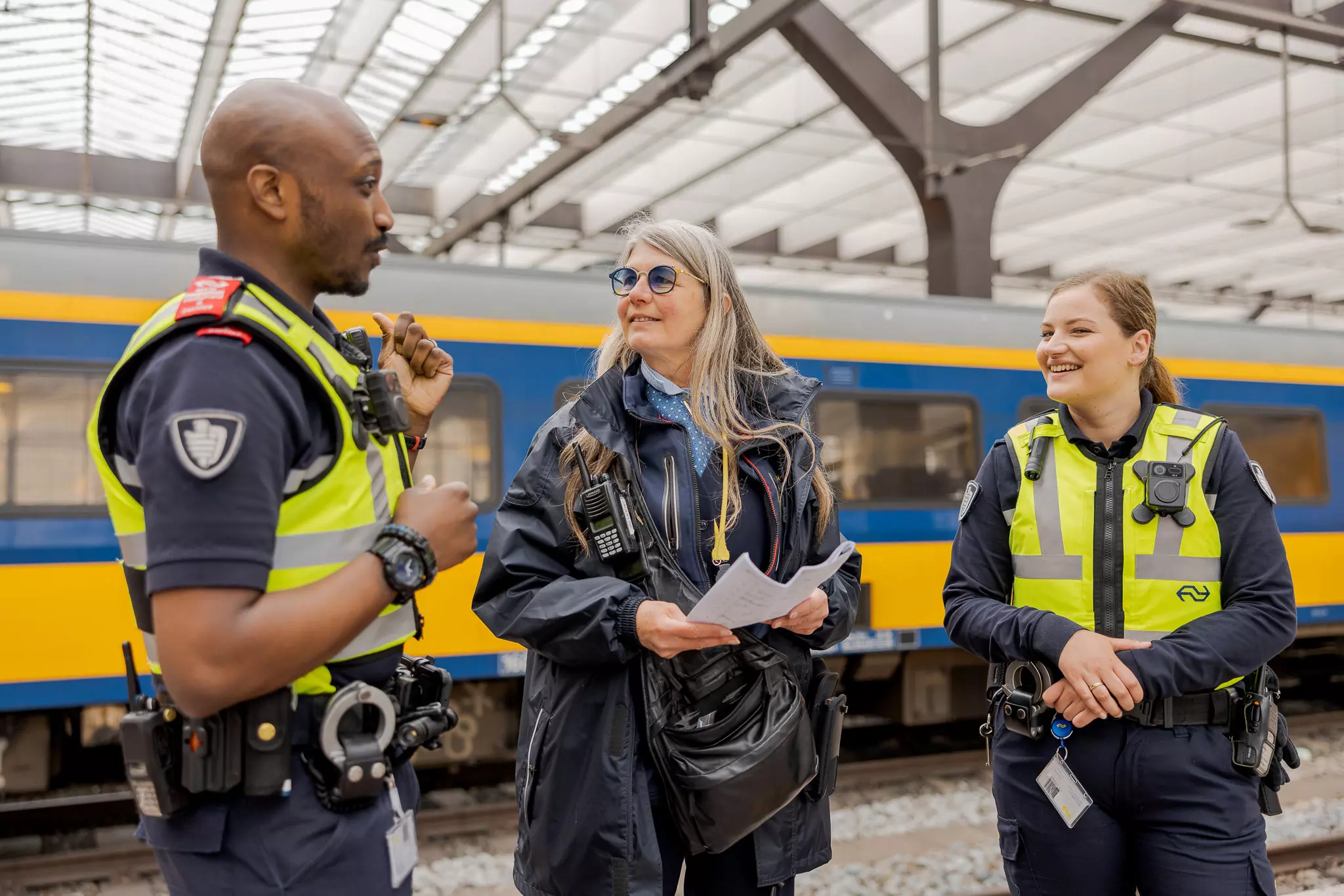 Twee medewerkers Veiligheid & Service zijn in gesprek met een conducteurs op het station van NS. 